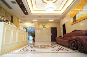 A hotel lobby with a reception desk, a sofa, a chandelier, and a patterned floor.