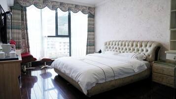 Un dormitorio con una cama grande, un escritorio de madera, una silla y una ventana con cortinas.