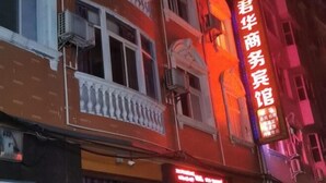 A building with a prominent red sign with white Chinese characters, indicating a business or service establishment. - Xuan'en Junhua Hotel (Xuan'en)