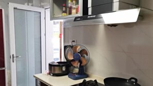 A kitchen with a gas stove, a fan, and a microwave. - Xuan'en Junhua Hotel (Xuan'en)