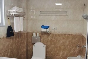 Un baño con inodoro, ducha y toallero.