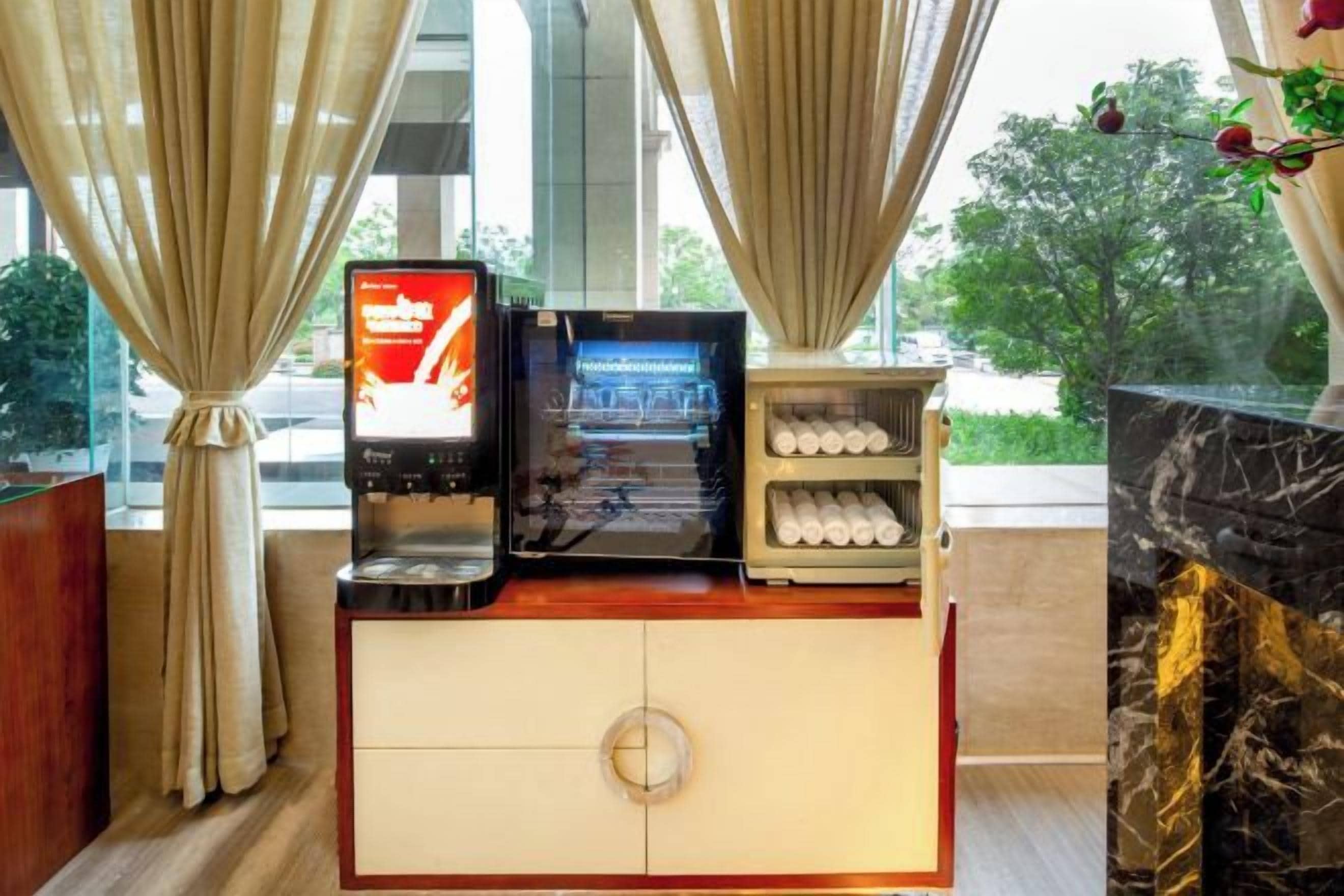 A hotel room with a minibar, a digital screen, and a marble fireplace.