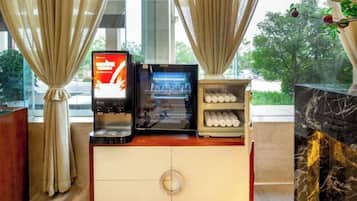 A hotel room with a minibar, a digital screen, and a marble fireplace.
