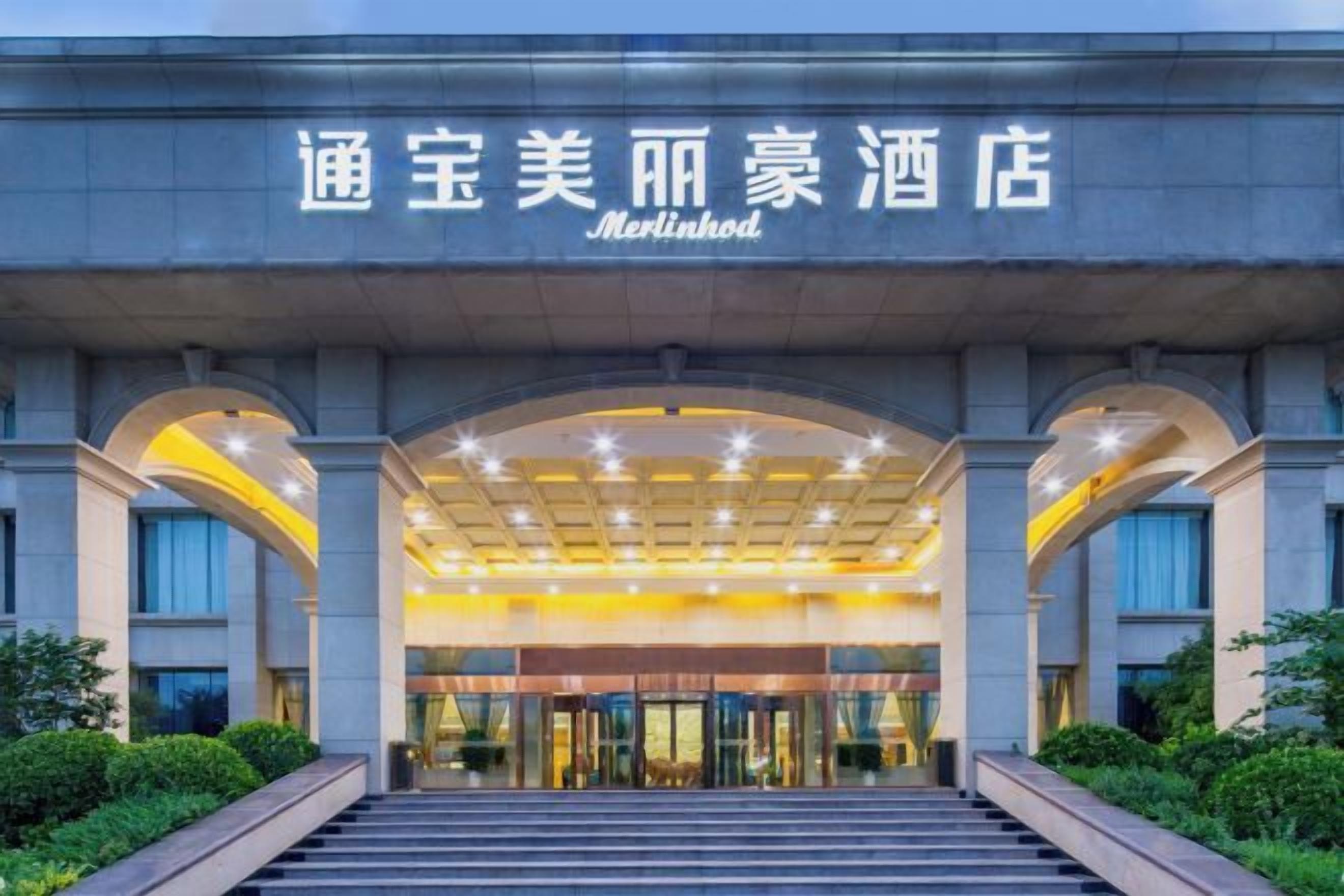 A hotel entrance with a modern design, featuring a large arched entrance and a well-lit facade.
