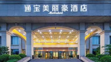 A hotel entrance with a modern design, featuring a large arched entrance and a well-lit facade.