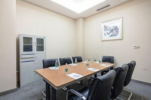 A conference room with a long table, black chairs, water bottles, and a cabinet. - Merlinhod Hotel (Yuncheng Airport, North Railway Station) (Yuncheng)