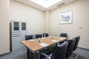 A conference room with a long table, black chairs, water bottles, and a cabinet.
