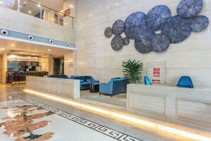 A hotel lobby with a reception desk, seating area, and a decorative wall. - Merlinhod Hotel (Yuncheng Airport, North Railway Station) (Yuncheng)