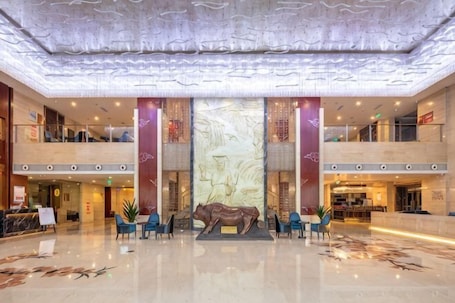 A spacious lobby with a marble floor, a large wall mural, and a reception desk.. Merlinhod Hotel (Yuncheng Airport, North Railway Station)