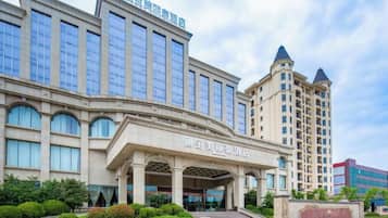 A hotel with a prominent entrance, multiple floors, and a fountain in the foreground.