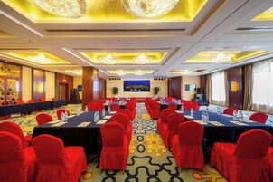 Un salón de conferencias con una mesa larga, sillas rojas y piso alfombrado.