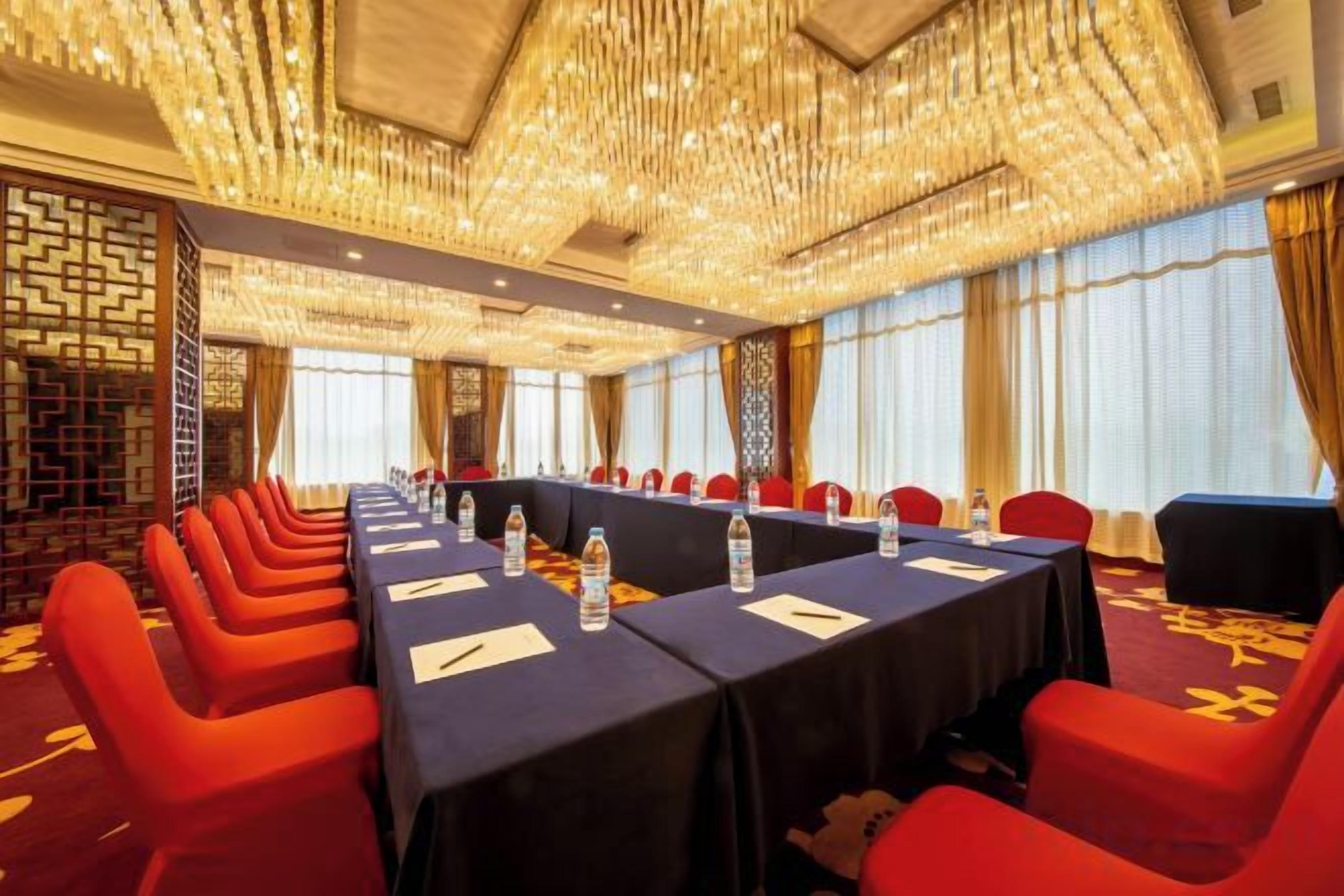 A conference room with a long table, red chairs, and a chandelier.