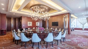 A conference room with a round table, multiple chairs, a chandelier, and a patterned carpet.