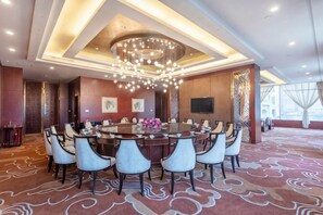 A conference room with a round table, multiple chairs, a chandelier, and a patterned carpet. - Merlinhod Hotel (Yuncheng Airport, North Railway Station) (Yuncheng)