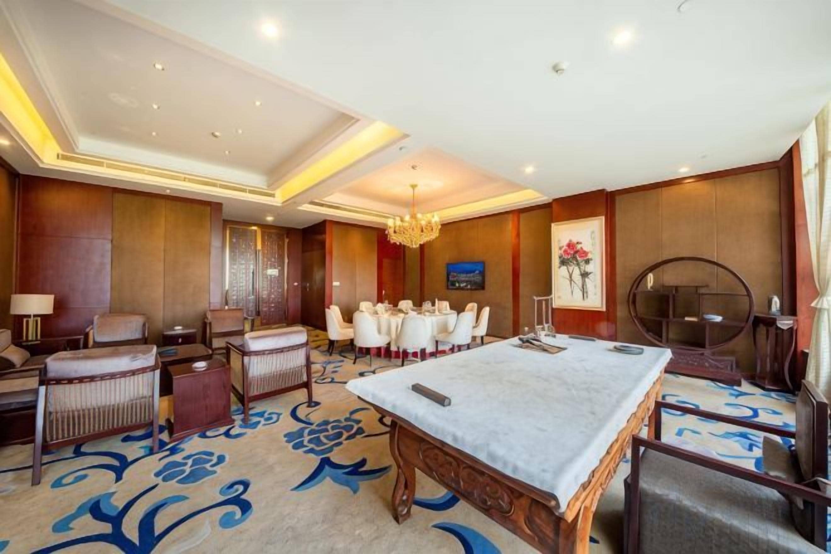A hotel room with a dining area, a pool table, and a large chandelier.