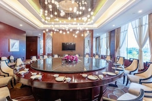 A conference room with a round table, chairs, a TV, and a chandelier. - Merlinhod Hotel (Yuncheng Airport, North Railway Station) (Yuncheng)