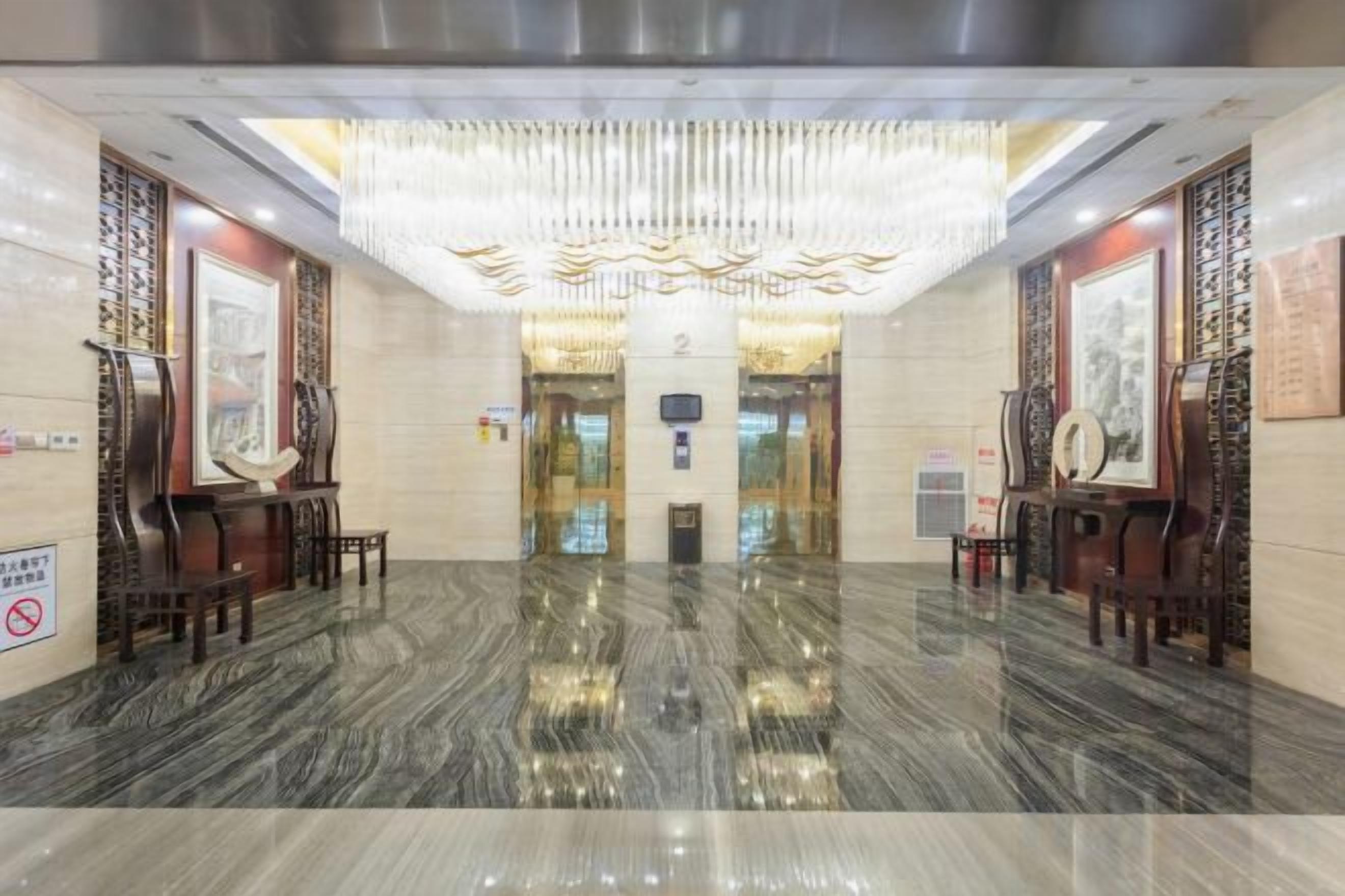 A lobby with a polished marble floor, a chandelier, and traditional decor.