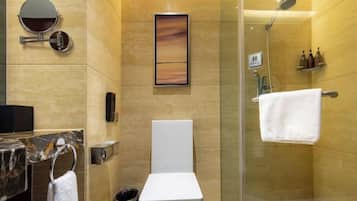 A modern bathroom with a toilet, a glass-enclosed shower, a marble sink, and a towel rack.