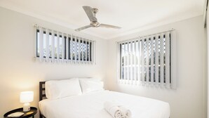 A hotel room with a bed, a nightstand with a lamp, and a ceiling fan.