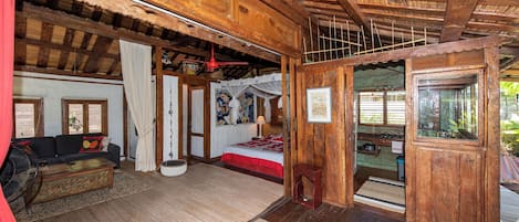 A wooden cabin with a living area, a bed, and a small dining area.