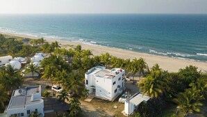 Een kustresort met witte gebouwen, palmbomen en uitzicht op het strand.