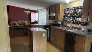 A kitchen with wooden cabinets, a central island, a sink, and a stove. - Charming 4-bedroom mobile home with WiFi and AC in Timberon (Timberon)