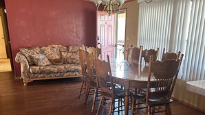 A dining room with a wooden table and chairs, a floral sofa, and a chandelier. - Charming 4-bedroom mobile home with WiFi and AC in Timberon (Timberon)