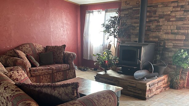 A living room with a patterned sofa, a fireplace, and a stone wall. - Charming 4-bedroom mobile home with WiFi and AC in Timberon (Timberon)