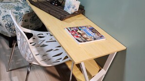 Un pequeño espacio de trabajo con un escritorio de madera, un globo terráqueo, una caja de pañuelos y una revista.