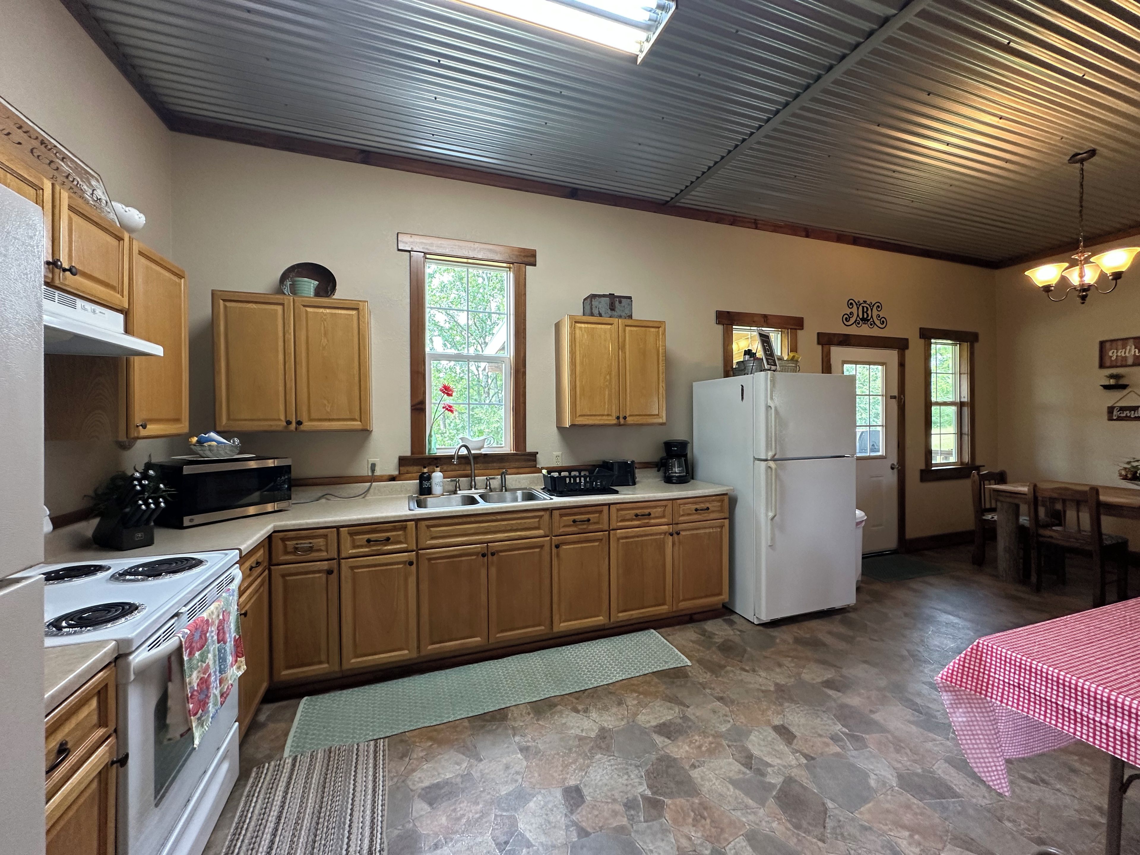 A kitchen with wooden cabinets, a white refrigerator, a stove, a sink, and a window with a flower.