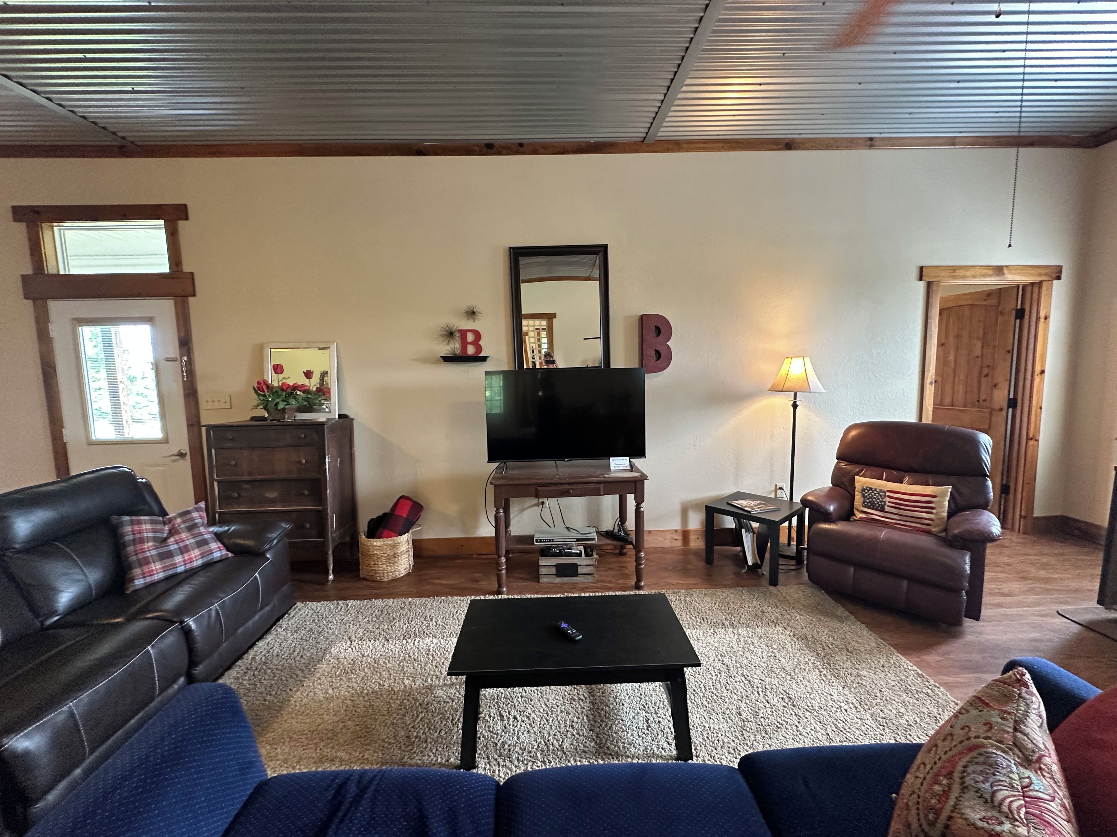 A living room with a leather sofa, a television, a coffee table, and a fireplace.
