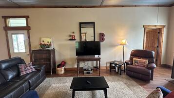 A living room with a leather sofa, a television, a coffee table, and a fireplace.