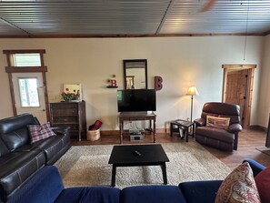 A living room with a leather sofa, a television, a coffee table, and a fireplace.