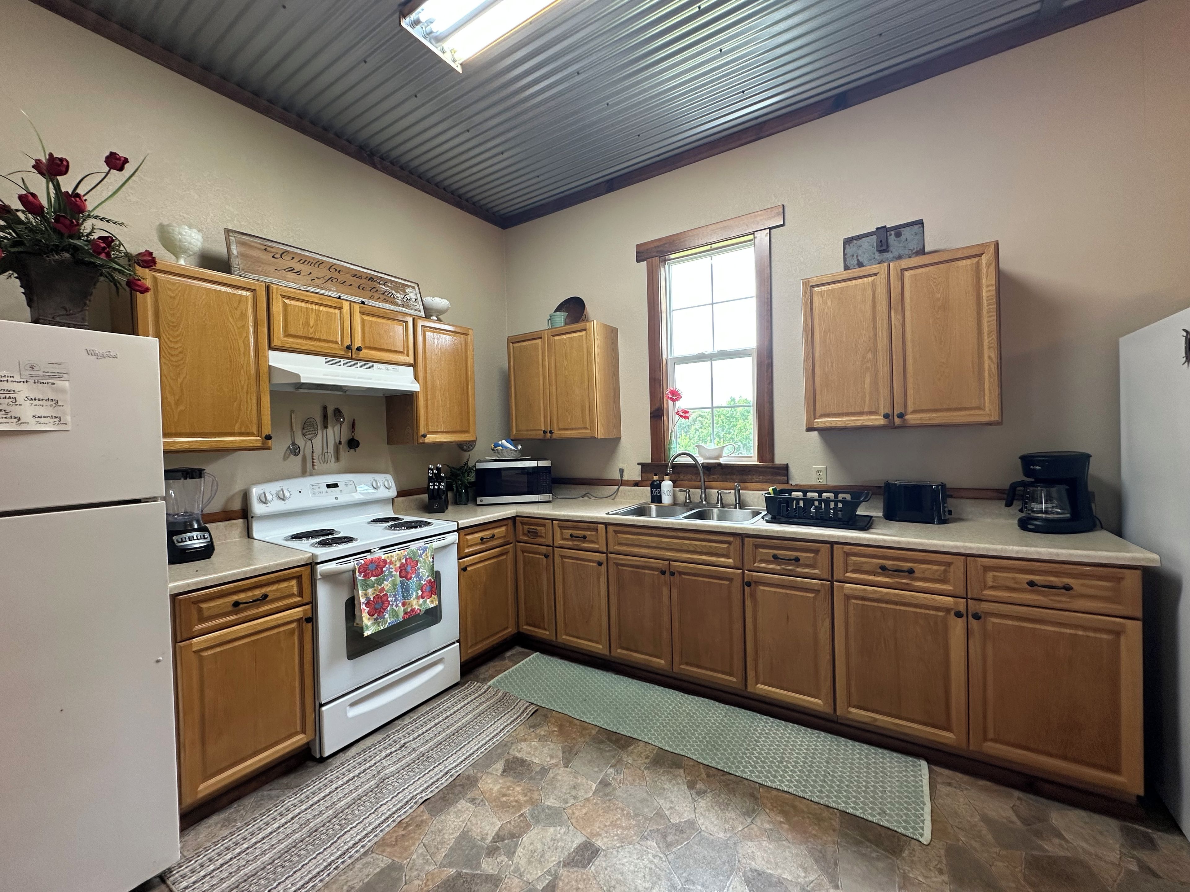 A kitchen with wooden cabinets, a white refrigerator, a stove, a microwave, and a sink.