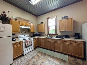 A kitchen with wooden cabinets, a white refrigerator, a stove, a microwave, and a sink.