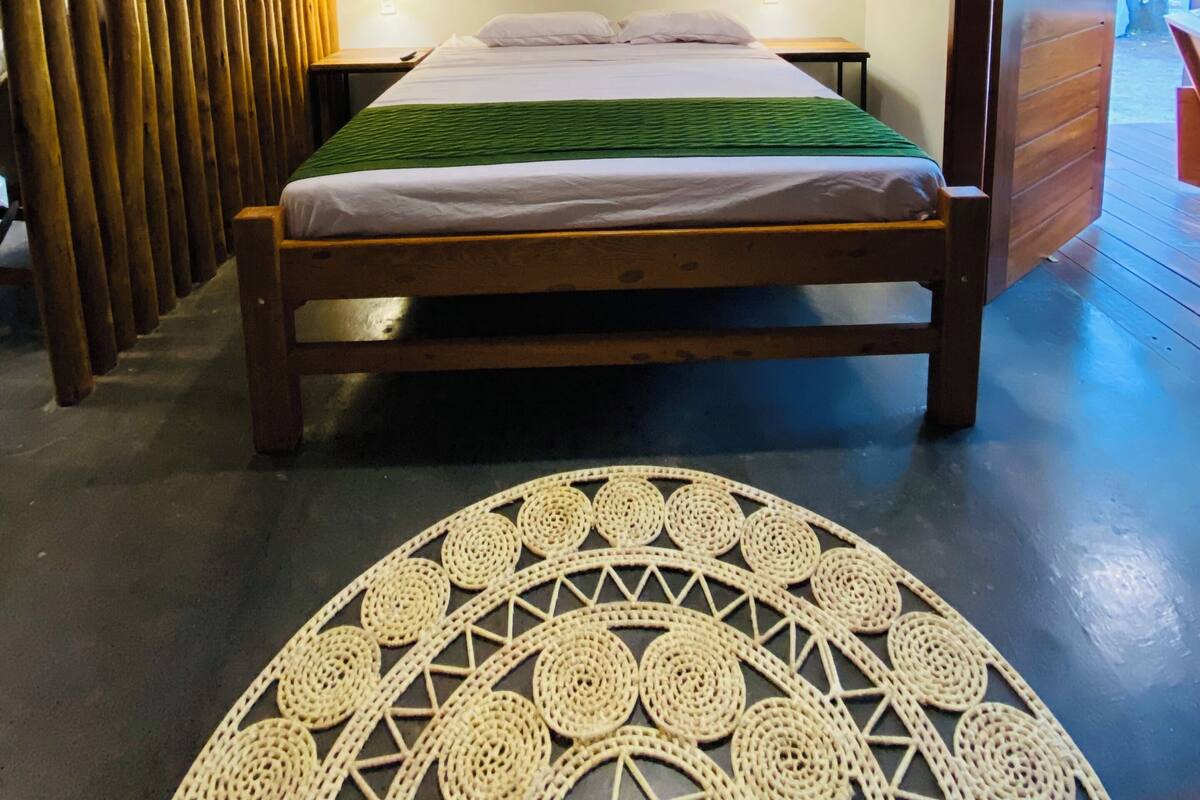 Una stanza con un letto, un lampadario a sospensione, una lampada a parete e un tappeto decorato.