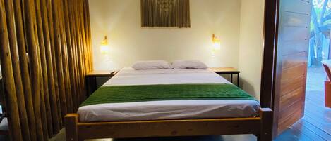 A room with a bed, a hanging light fixture, a wall-mounted lamp, and a patterned rug.
