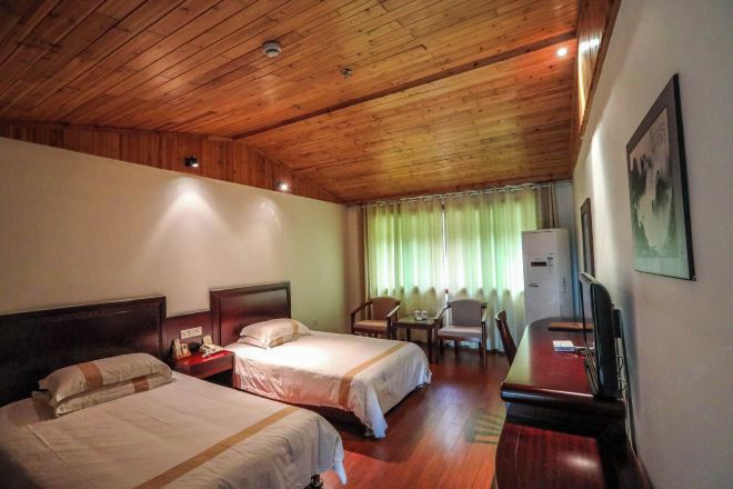 A hotel room with two beds, a desk, a chair, a television, and a window with curtains.