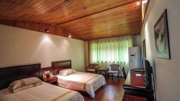 A hotel room with two beds, a desk, a chair, a television, and a window with curtains.
