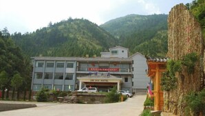 A hotel with a modern building and traditional architecture, surrounded by lush green hills. - Jin Xiu Hotel (Yushan)