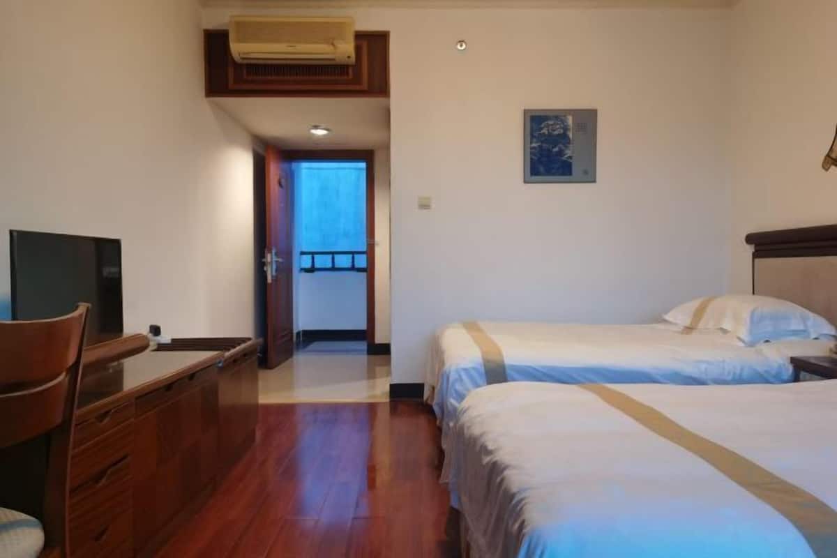 A hotel room with two beds, a desk, and a television.