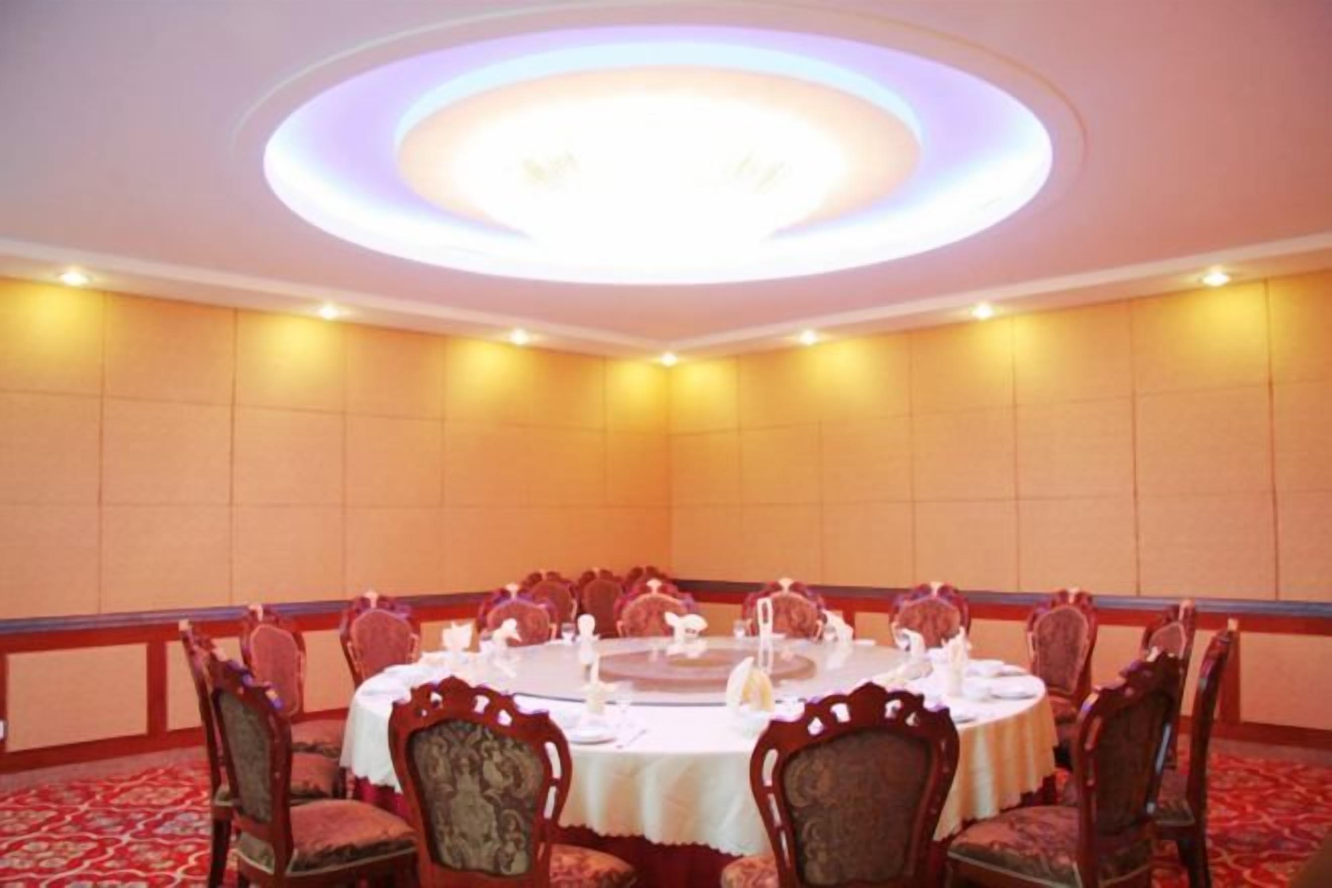 A conference room with a round table, chairs, and a ceiling light fixture.