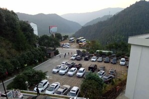 A parking lot with multiple cars and a few buses, surrounded by greenery and hills. - Jin Xiu Hotel (Yushan)