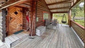 Une cabane en rondins avec une véranda, une chaise berçante et une balançoire.