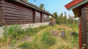 Une cabane rustique en rondins de bois, dotée d’un porche en bois et d’un petit escalier menant à l’entrée.