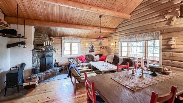 L’intérieur d’un chalet confortable, avec une cheminée en pierre, des meubles en bois et une table à manger.