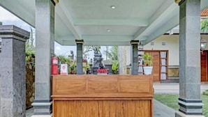 Ein Empfangsschalter mit Holzoptik, flankiert von Steinpfeilern, und eine Statue im Hintergrund.