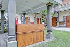 Un espace d’accueil avec un comptoir en bois, des colonnes et une plante en pot.