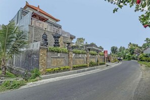 Un bâtiment traditionnel doté d’une entrée fermée par un portail, d’un chemin sinueux et d’une végétation luxuriante.