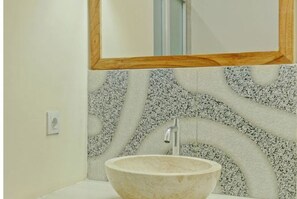 Un baño con un lavabo de piedra, un espejo y una pared con textura.